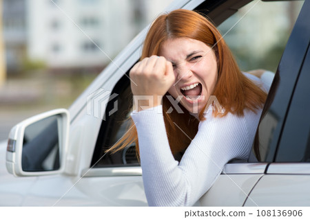 Closeup portrait of pissed off displeased angry aggressive woman driving a car shouting at someone with hand fist up. Negative human expression consept. Closeup portrait of pissed off displeased angry aggressive woman driving a car shouting at someone with hand fist up. Negative human expression consept. 108136906