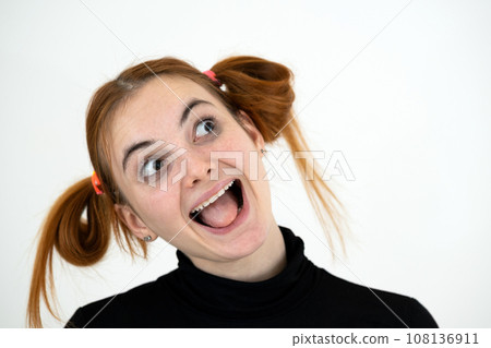 Closeup portrait of a funny redhead teenage girl with childish hairstyle smiling happily isolated on white backround. Closeup portrait of a funny redhead teenage girl with childish hairstyle smiling happily isolated on white backround. 108136911