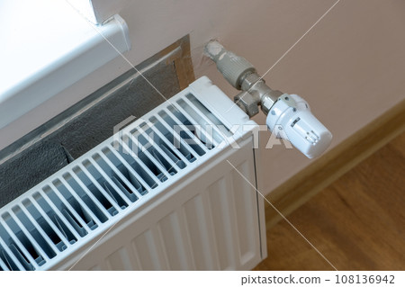 Closeup of heating radiator valve for comfortable temperature regulation on metal radiator on inrerior wall. 108136942