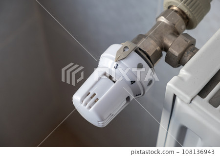 Closeup of heating radiator valve for comfortable temperature regulation on metal radiator on inrerior wall. Closeup of heating radiator valve for comfortable temperature regulation on metal radiator on inrerior wall. 108136943