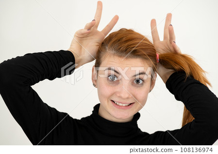 Close up portrait of funny girl holding her ears with hands like a monkey. Close up portrait of funny girl holding her ears with hands like a monkey. 108136974