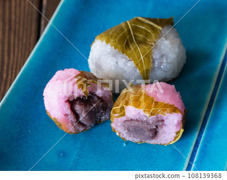 A cross section of pink and white Domyoji Sakuramochi with red bean paste inside. 108139368
