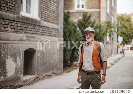 Portrait of handsome senior man in a city. Elderly cool man strolling through city in fashionable clothes. Portrait of handsome senior man in a city. Elderly cool man strolling through city in fashionable clothes. 108139690