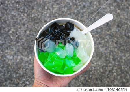 Thai Shaved Ice or Nam-Kang-Sai in paper cup in hand, top view 108140254