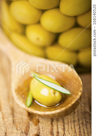 Close up green olives in wooden spoon, rosemary on a wooden background Close up green olives in wooden spoon, rosemary on a wooden background 108140520