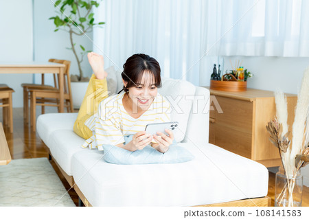 A young woman operating a smartphone in a room A young woman operating a smartphone in a room 108141583