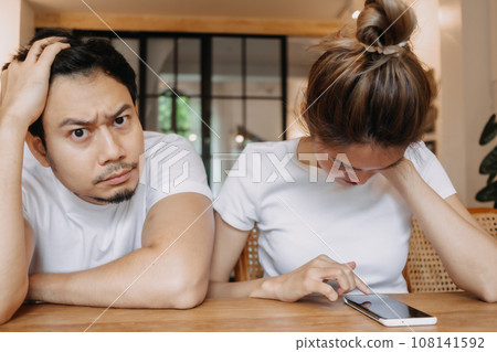 Man gets bored as woman chats on the phone for long time. Asian couple in cafe Man gets bored as woman chats on the phone for long time. Asian couple in cafe 108141592