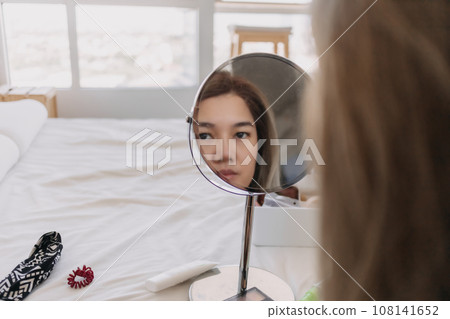 Woman wearing make up at the mirror with tools and equipments. Woman wearing make up at the mirror with tools and equipments. 108141652