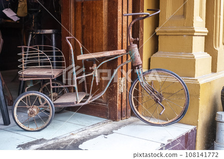 Broken tricycle near house in Thailand Broken tricycle near house in Thailand 108141772