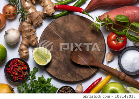 Wooden cutting board, wooden spoon, vegetables and spices 108142035