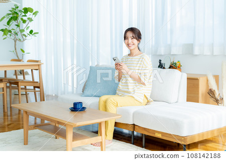 A young woman operating a smartphone in a room A young woman operating a smartphone in a room 108142188