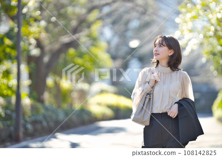 Young woman walking outdoors in suit Young woman walking outdoors in suit 108142825