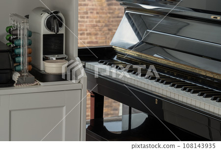 Living room interior with Automatic coffee machine, Coffee capsules on white wooden shelf and grand piano. 108143935