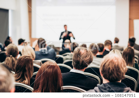 Speaker giving a talk in conference hall at business event. Rear view of unrecognizable people in audience at the conference hall. Business and entrepreneurship concept Speaker giving a talk in conference hall at business event. Rear view of unrecognizable people in audience at the conference hall. Business and entrepreneurship concept 108147051