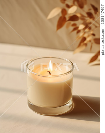 Minimalist burning wax candle in clear glass on natural beige stone background with copy space, styled commercial product mockup Minimalist burning wax candle in clear glass on natural beige stone background with copy space, styled commercial product mockup 108147497