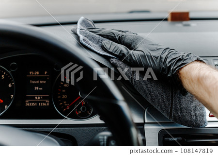 Man's hand in black glove cleaning car interior, dashboard and leather seats with microfiber cloth Man's hand in black glove cleaning car interior, dashboard and leather seats with microfiber cloth 108147819
