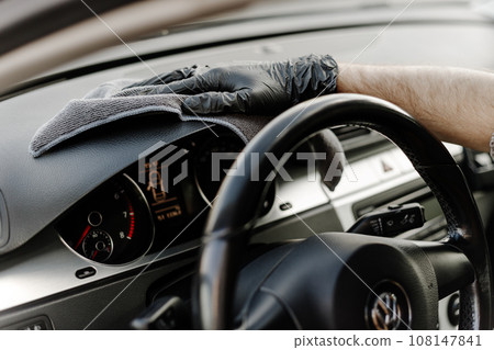 Man's hand in black glove cleaning car interior, dashboard and leather seats with microfiber cloth Man's hand in black glove cleaning car interior, dashboard and leather seats with microfiber cloth 108147841