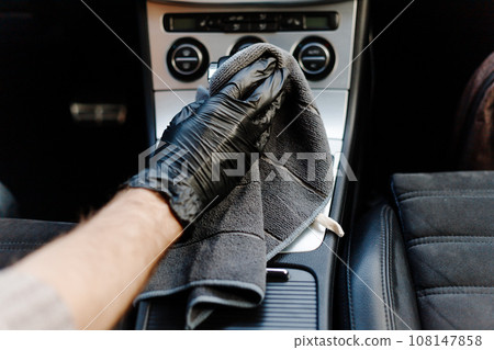 Man's hand in black glove cleaning car interior, dashboard and leather seats with microfiber cloth Man's hand in black glove cleaning car interior, dashboard and leather seats with microfiber cloth 108147858