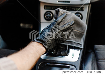 Man's hand in black glove cleaning car interior, dashboard and leather seats with microfiber cloth Man's hand in black glove cleaning car interior, dashboard and leather seats with microfiber cloth 108147883