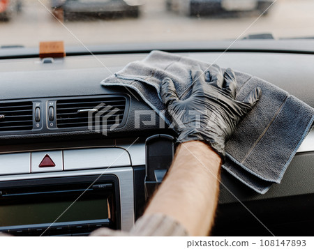 Man's hand in black glove cleaning car interior, dashboard and leather seats with microfiber cloth Man's hand in black glove cleaning car interior, dashboard and leather seats with microfiber cloth 108147893