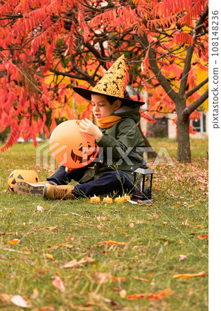 Happy Halloween kid playing with pumpkin balloon in park in autumn. Happy Halloween kid playing with pumpkin balloon in park in autumn. 108148236