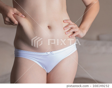 The girl tightens the skin on her stomach, showing fat deposits in the abdomen and sides. fat woman The girl tightens the skin on her stomach, showing fat deposits in the abdomen and sides. fat woman 108149232