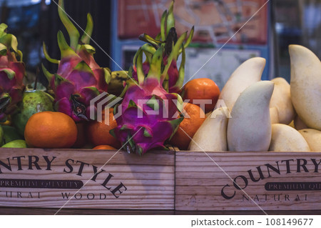 Mixed tropical fruits heap in wooden box sale on street market. Crate box full of fresh exotic various vegetables from organic farm 108149677