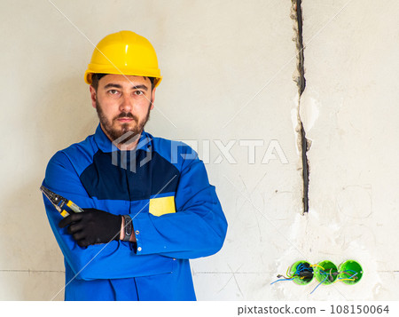 Portrait of worker or engineer in blue work clothes and yellow safety helmet 108150064