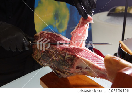 Sliced dried chamon prosciutto. A man cuts a jamon, a warm toned image. Selective focus point. Sliced dried chamon prosciutto. A man cuts a jamon, a warm toned image. Selective focus point. 108150506