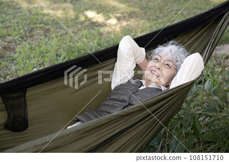 Senior woman laughing while riding in a hammock 108151710