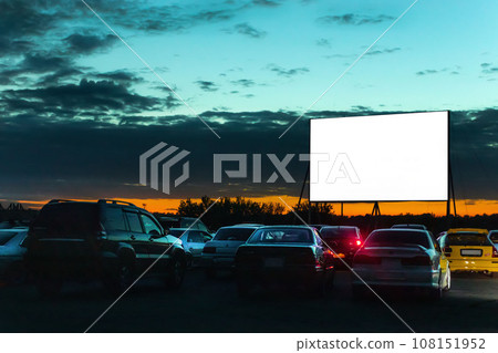 Parked cars to watch movies inside the car. Car cinema, open air cinema, open to public. Photo at sunset, night. 108151952
