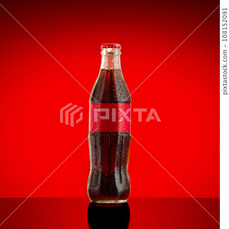 Cola soft drink in a glass bottle on red Background. Cola soft drink in a glass bottle on red Background. 108152091