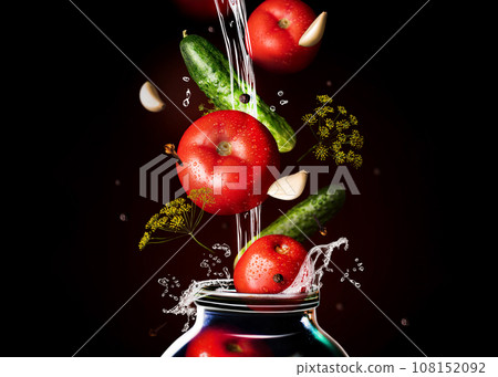 Canned tomatoes and cucumber in glass. Black background, horizontal. Food levitation, tomatoes, garlic, peppers and dill in the air. Canning, fermentation, pickles Canned tomatoes and cucumber in glass. Black background, horizontal. Food levitation, tomatoes, garlic, peppers and dill in the air. Canning, fermentation, pickles 108152092