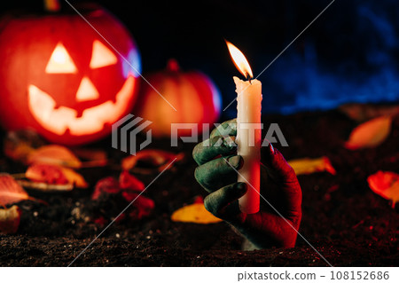 Horrible zombie hand emerges from grave on cemetery with candle.Undead,halloween 108152686