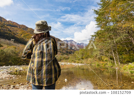 A woman looking at Mt. Tanigawa from the Yuhiso River in autumn 108152709