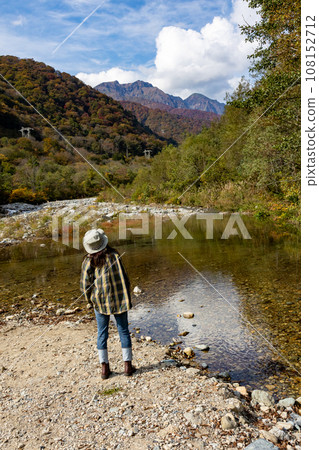 A woman looking at Mt. Tanigawa from the Yuhiso River in autumn 108152712
