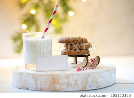 Nice Christmas tradition milk for Santa. Milk, cookies on Santa's sleigh, empty note on wooden stand 108153390