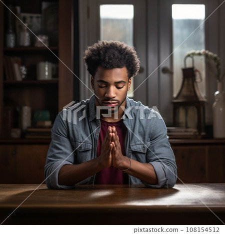 Young man praying at home, hands folded Young man praying at home, hands folded 108154512