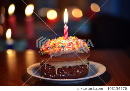 Hamburger with lit birthday candle on blurry backdrop Hamburger with lit birthday candle on blurry backdrop 108154576