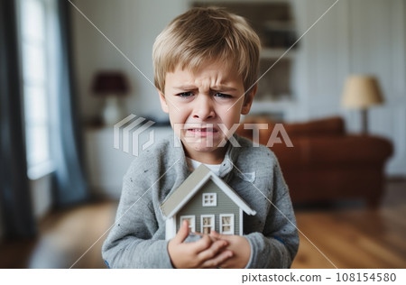 Upset 6 year old boy crying while clutching a small house in his hands Upset 6 year old boy crying while clutching a small house in his hands 108154580
