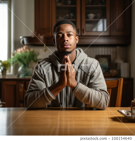 Young man praying at home, hands folded Young man praying at home, hands folded 108154640