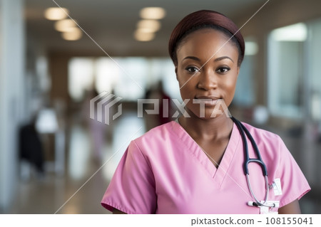 Portrait of beautiful smiling female doctor or nurse wearing pink uniform standing in medical facility. Young African American medical practitioner with stethoscope. Healthcare and treatment concept. 108155041