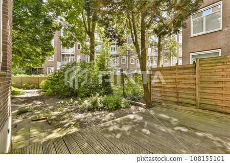 an outside area with wooden decking and trees in the fore - image is taken from above, looking towards the back yard 108155101