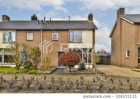 two houses in the netherlands, one is red brick and the other is blue sky with white clouds above them 108155115