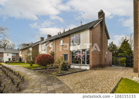 a house in the middle of a garden with trees and shrubs on either side of the house there is a path leading up to the front door 108155133