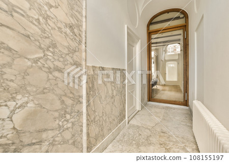 a hallway with marble walls and flooring in an apartment or residential building, taken from the front door to the entrance way a hallway with marble walls and flooring in an apartment or residential building, taken from the front door to the entrance way 108155197