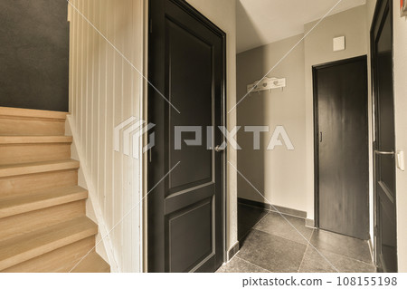 a hallway with black doors and wooden steps leading up to the second floor in an apartment or condo, which is for sale a hallway with black doors and wooden steps leading up to the second floor in an apartment or condo, which is for sale 108155198