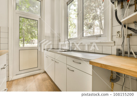 a kitchen with white cabinets and wood counter tops in front of a window that looks out to the trees outside 108155200