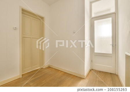 an empty room with white walls and wood flooring the door is open on the right side of the room an empty room with white walls and wood flooring the door is open on the right side of the room 108155263