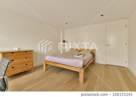 a bedroom with white walls and hardwood flooring in the room, there is an empty bed on the right side 108155291